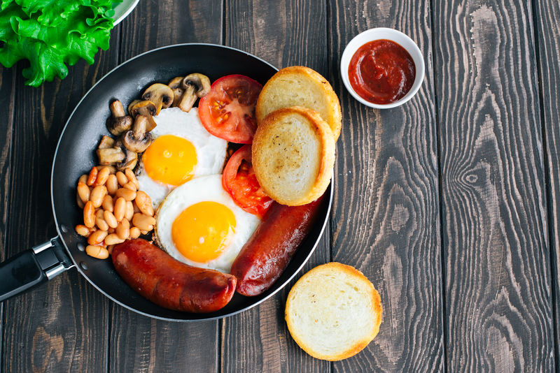 早餐番茄、香肠、豆类、蘑菇、鸡蛋、吐司和香草俯视图