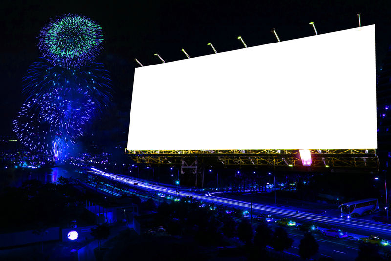 晚上在城市街道上放烟花的空白广告牌