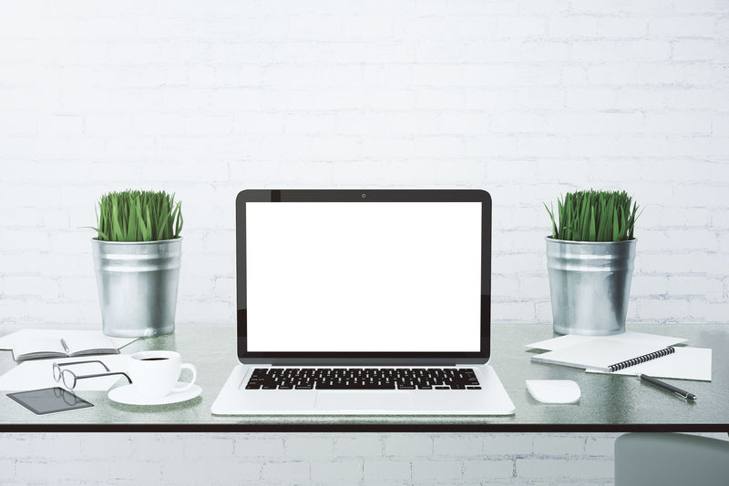 玻璃桌上的空白白色笔记本电脑屏幕和咖啡