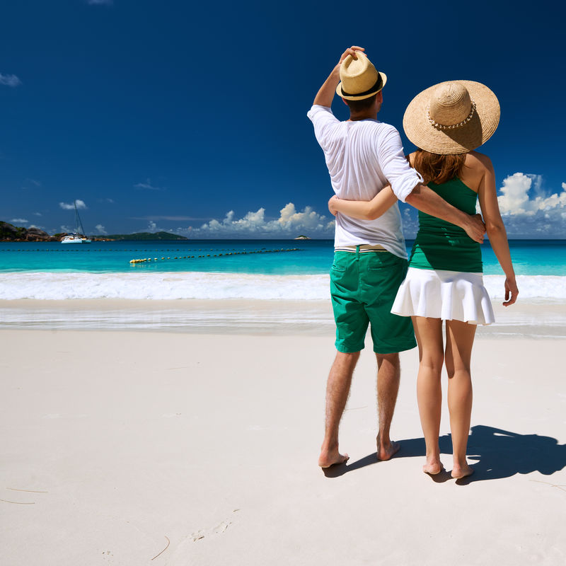 在塞舌尔的热带海滩上散步的一对绿色情侣