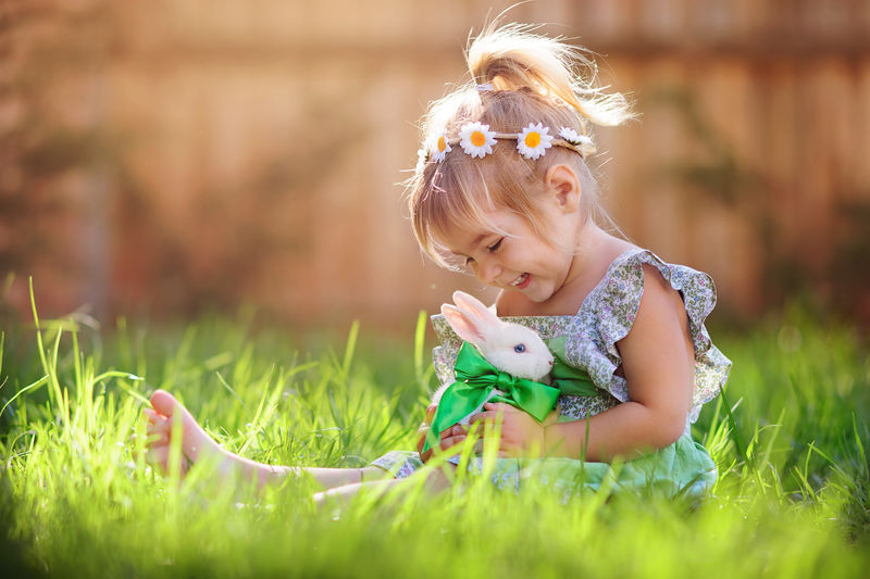 可爱的小女孩和兔子在绿草背景下过复活节