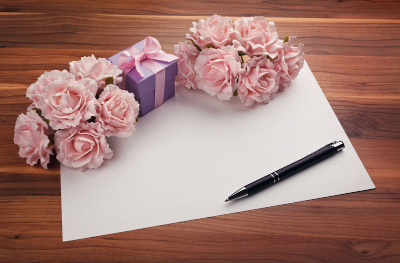带笔、粉红玫瑰和紫色礼品盒的贺卡