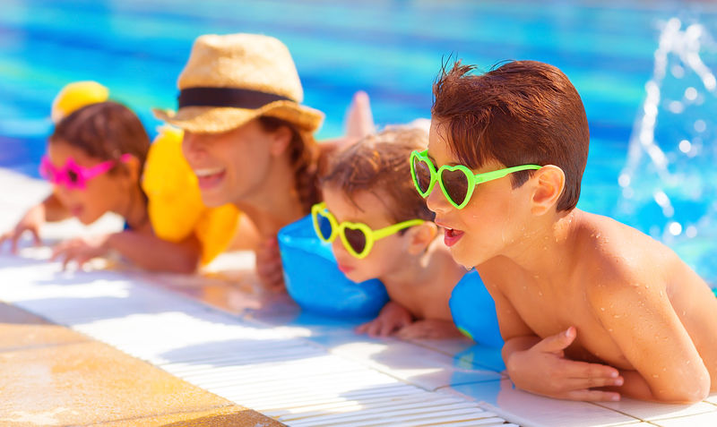快乐的家庭在游泳池里-在水里玩得开心-妈妈带着三个孩子在水上乐园-海滩度假-暑假-快乐的概念