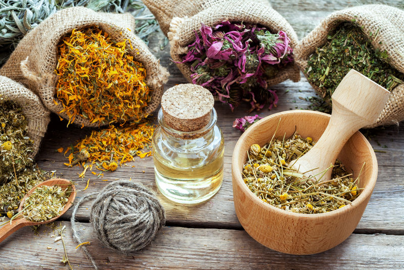 麻袋中的草药、洋甘菊研钵和木桌上的精油、草药