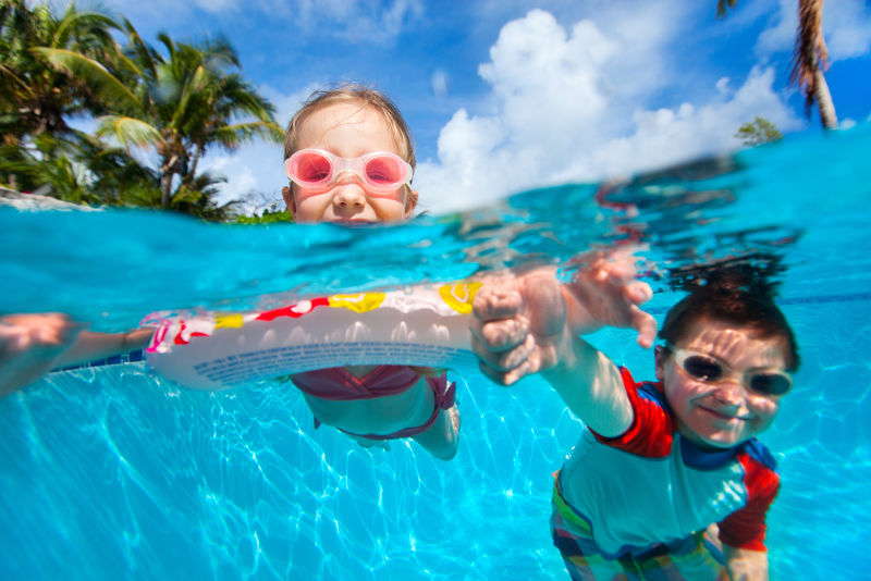 孩子们在游泳池里游泳的上面和水下照片