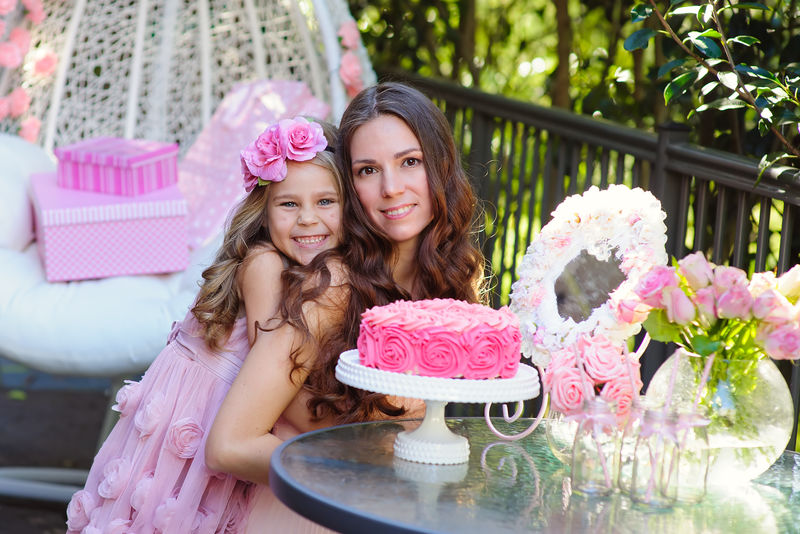 年轻漂亮的女人和女儿用蛋糕庆祝生日