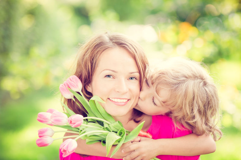 一个女人和一个孩子-在模糊的绿色背景下-开着一束花-春季家庭假日概念-妇女节