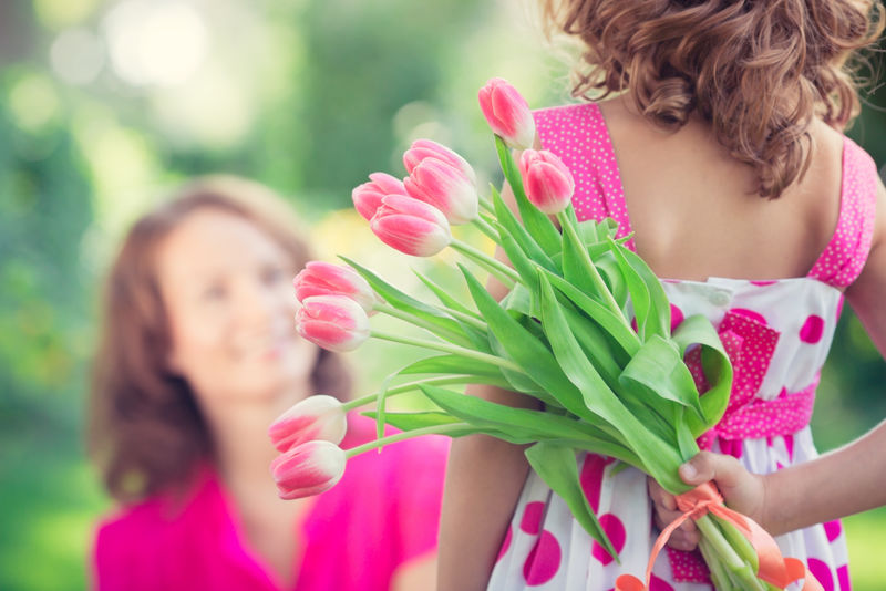 一个女人和一个孩子-在模糊的绿色背景下-开着一束花-春季家庭假日概念-妇女节