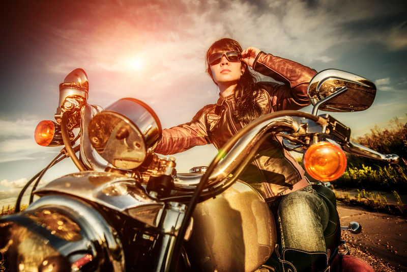 骑摩托车看日落时穿皮夹克的骑车女孩