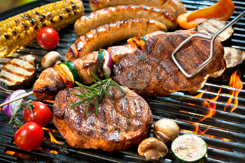 烧烤时在炭火上撒上各种美味的烤肉和蔬菜