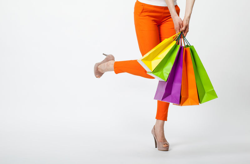 快乐购物！在橙色的裤子拿着五彩的购物袋面目全非的女人