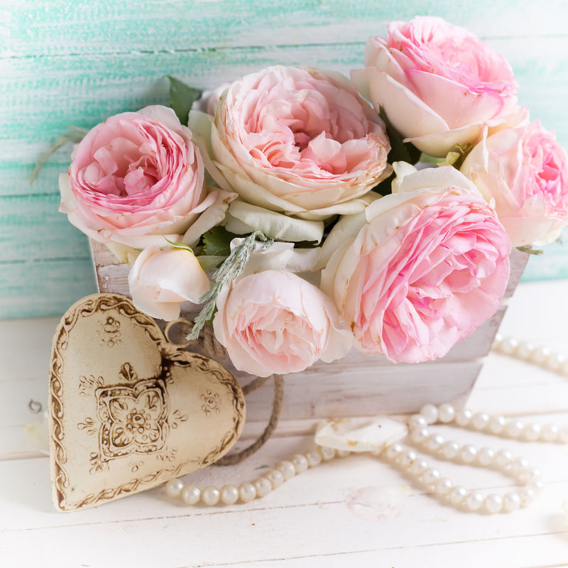 背景为粉红玫瑰花木盒和装饰性心形图案-背景为白漆木背景-衬绿松石墙-选择性聚焦-方形图像