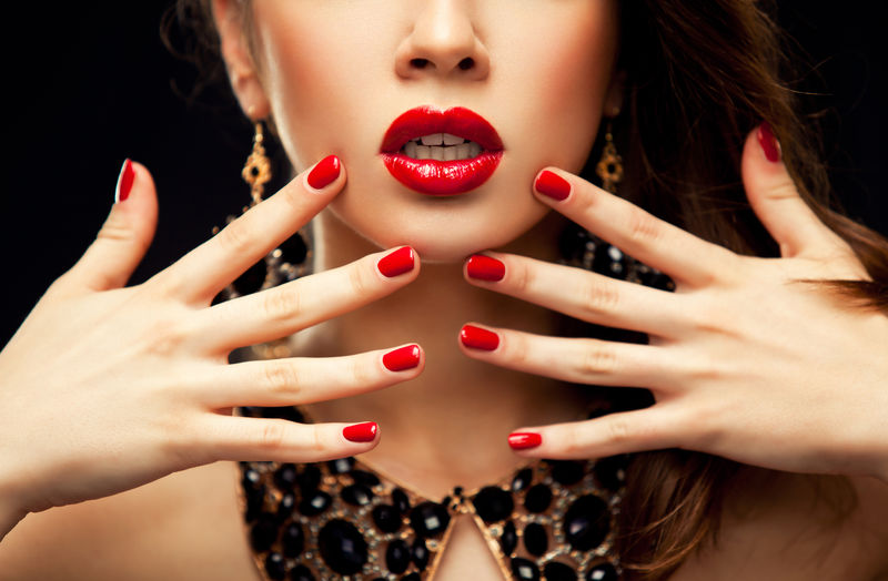 红色性感的嘴唇和指甲特写-张开嘴-美甲和化妆-化妆概念-有一半的美女模特脸与黑色背景隔离开来