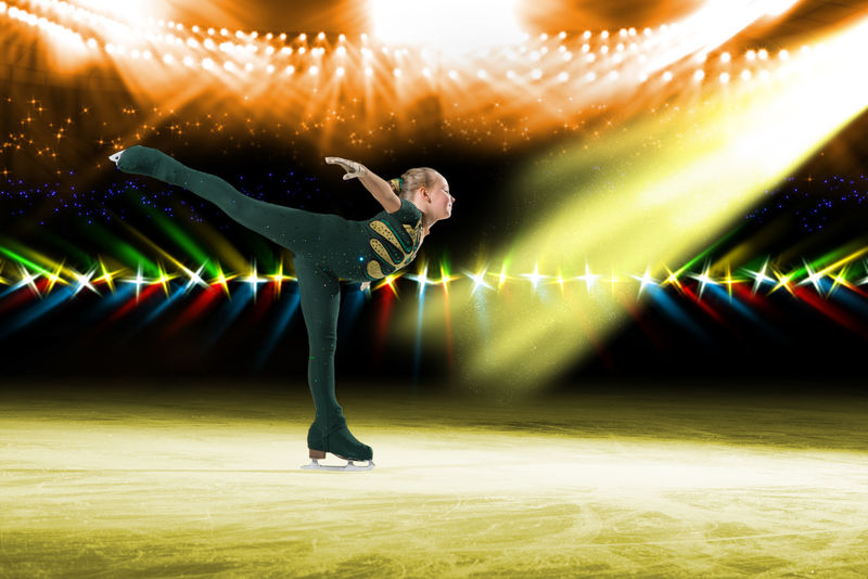 年轻的滑冰运动员在冰上表演-背景灯亮着