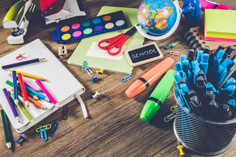 木制桌面上的彩色学校用品。回到学校
