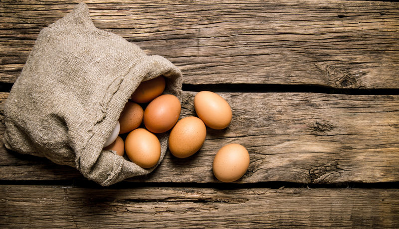 鸡蛋和旧袋子。在木桌上。