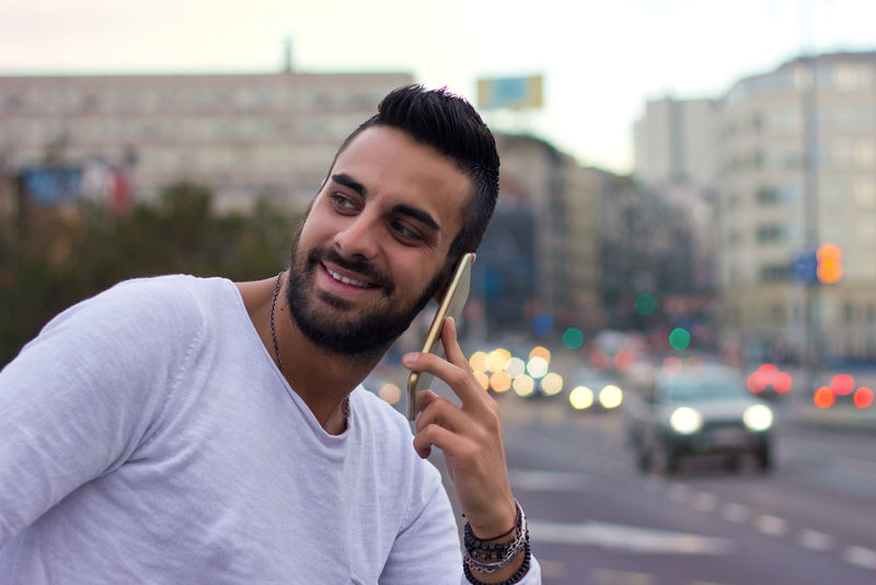 帅哥在户外打电话。穿着皮夹克，戴着太阳镜，留着胡子。Instagram效应。