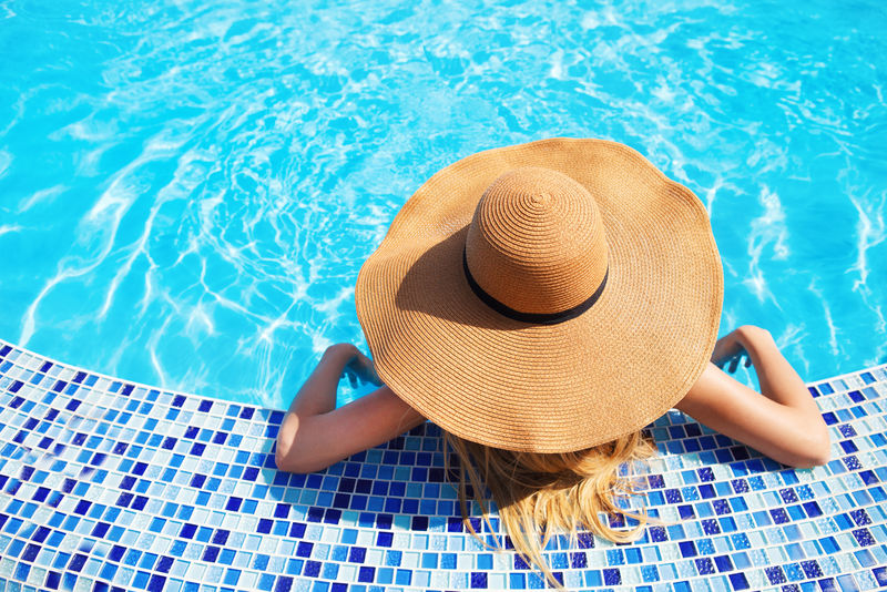 戴帽子的美女在游泳池里游泳