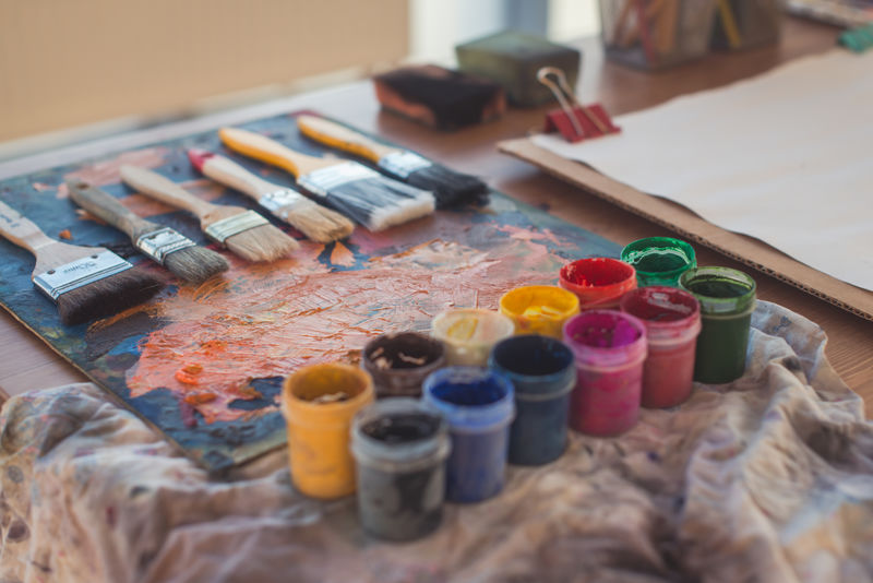 水粉画和水彩与画笔设置在艺术工作室的照片。涂在调色板上的油画