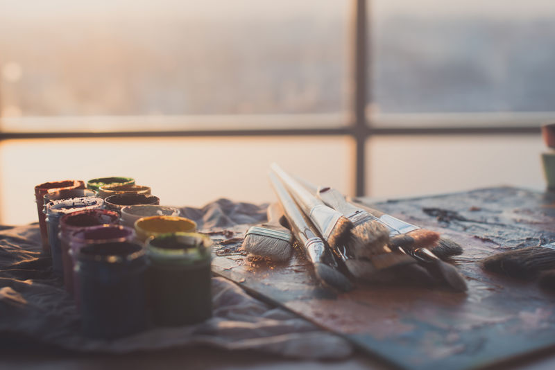 水粉画和水彩与画笔设置在艺术工作室的照片。涂在调色板上的油画