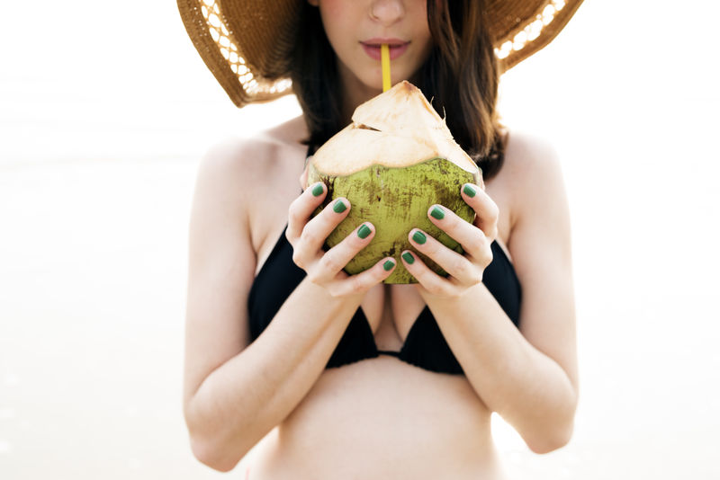女性饮用椰子海滩户外概念