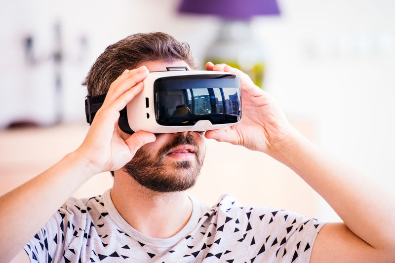 一个戴着虚拟现实眼镜的男人，坐在客厅里