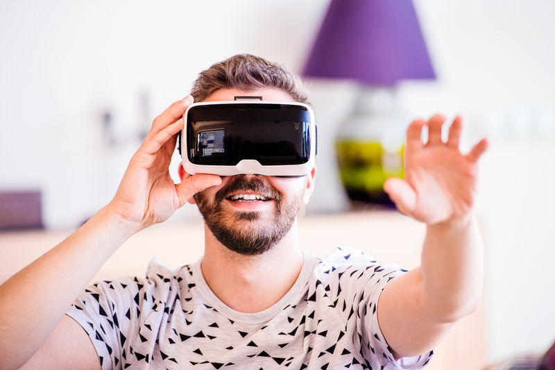 一个戴着虚拟现实眼镜的男人，坐在客厅里