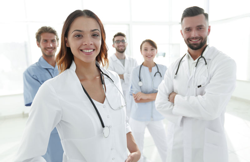 有魅力的女医生-带着医用听诊器站在医疗小组前面