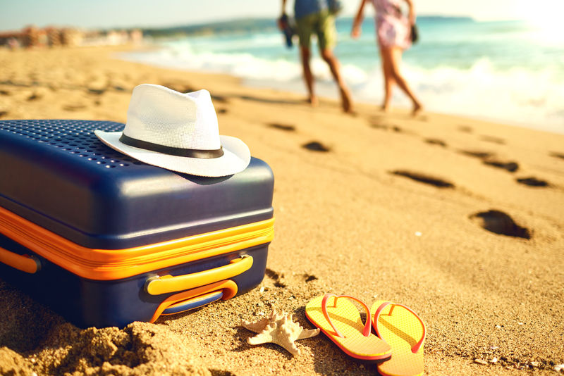 沙滩上的手提箱和帽子