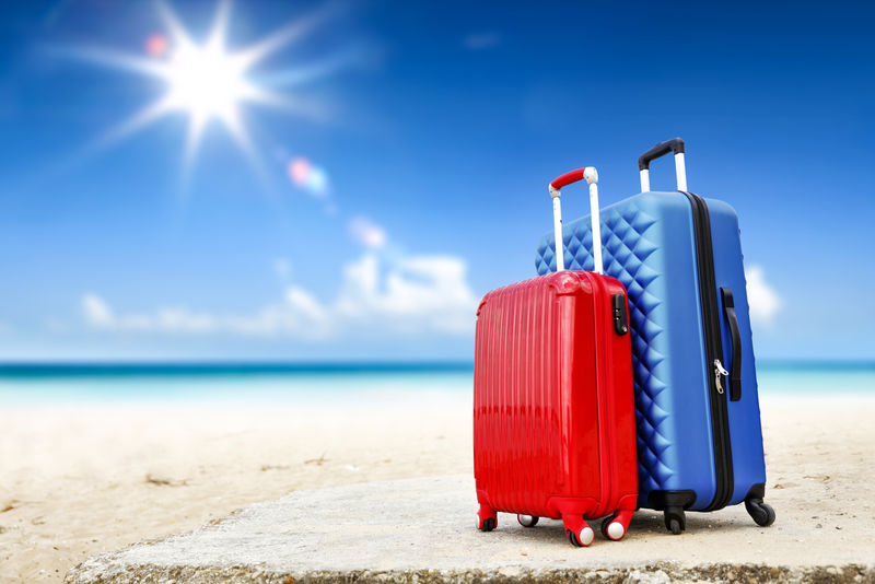 沙滩上的夏季旅行箱和海景-夏日阳光普照蓝天-为您的装饰或文字提供免费空间