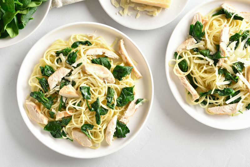 意大利面-菠菜叶意大利面-烤鸡胸肉片和磨碎的奶酪放在石板上-美味的蔬菜叶意大利面-健康食品-俯视图-平铺