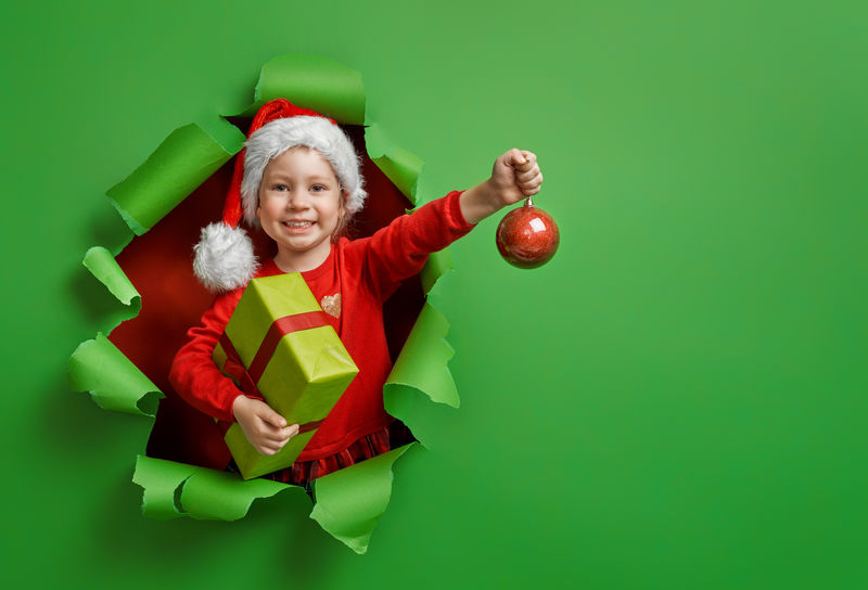 快乐的小女孩-在明亮的颜色背景上带着圣诞礼物-红色和绿色
