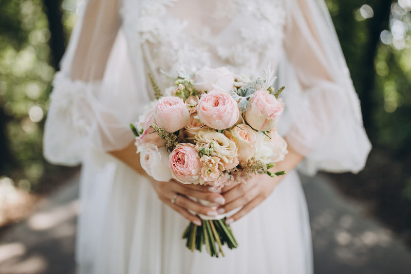 新娘身穿白色婚纱-手持一束玫瑰、牡丹和绿叶