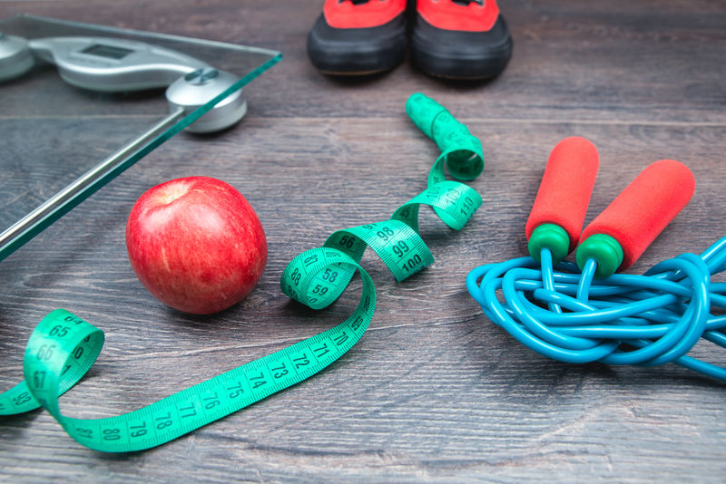 绿色卷尺-玻璃秤-跳绳和一个红苹果放在粗糙的表面上