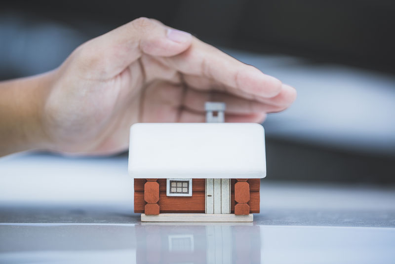 保险公司的概念-斯堪的纳维亚的房子模型和人的手-保护你的新财产