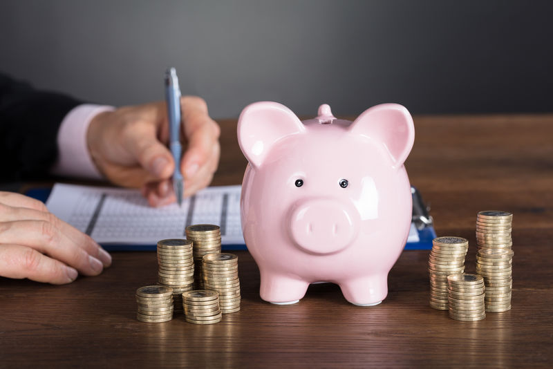 商人在木桌上用叠好的硬币和储蓄罐计算发票