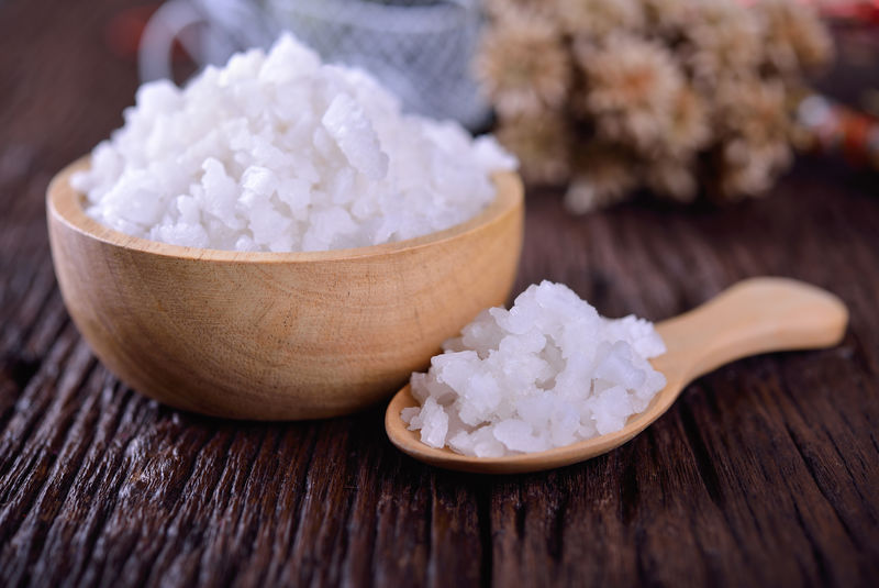 木制汤匙的盐和木制背景的碗