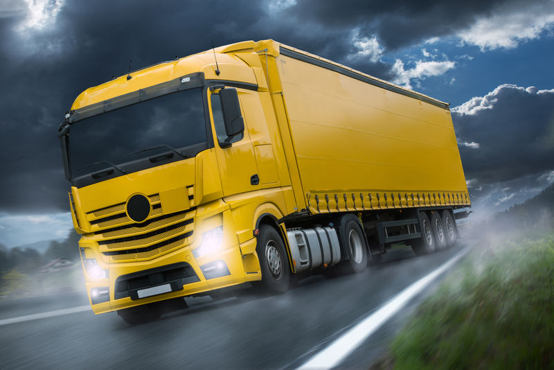 乡村公路上黄色拖车的白色卡车迎着蓝天和阳光