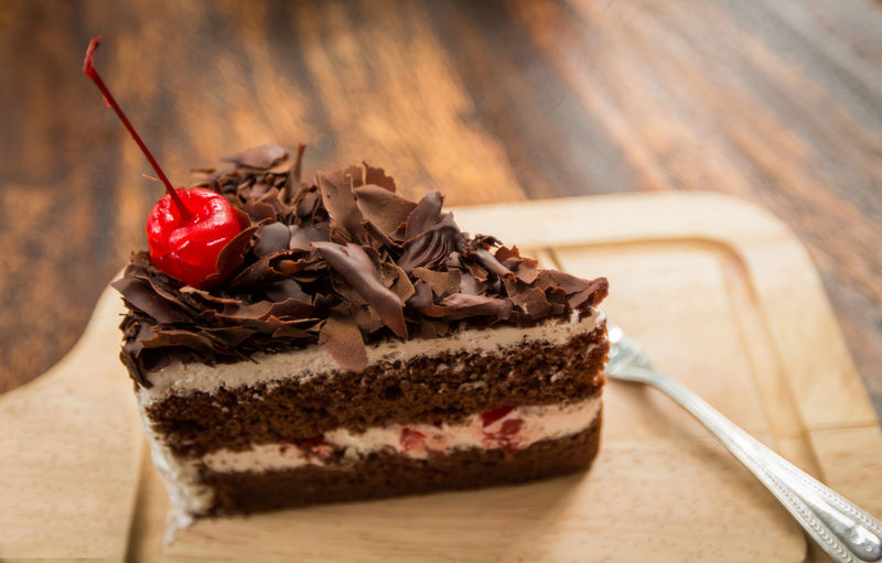 木桌上放着樱桃的巧克力蛋糕