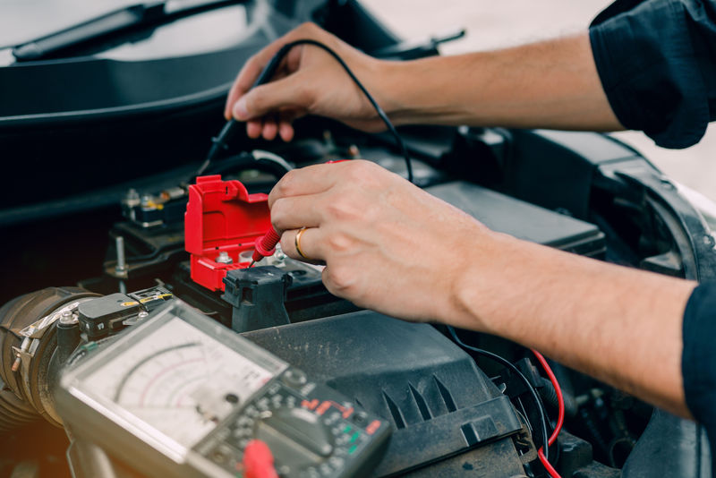 汽车修理工正在使用汽车电池表来测量和分析各种数值
