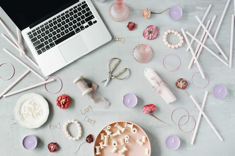 平躺顶视图办公桌工作区配有笔记本电脑紫色蜡烛线轴套件装饰金色剪刀和灰色水泥背景的夹子