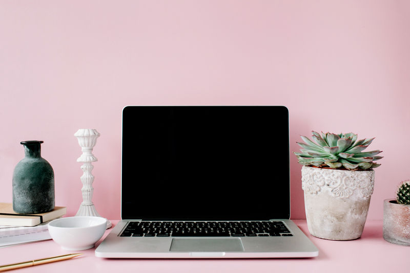 桌子上有粉红背景的黑屏笔记本电脑