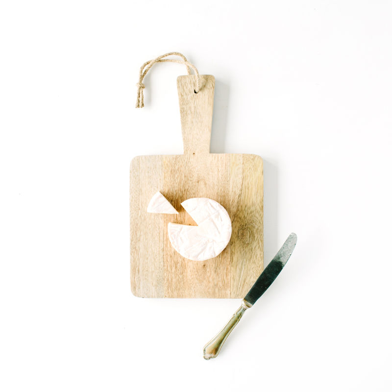 白底木制砧板上的卡门伯奶酪和小刀