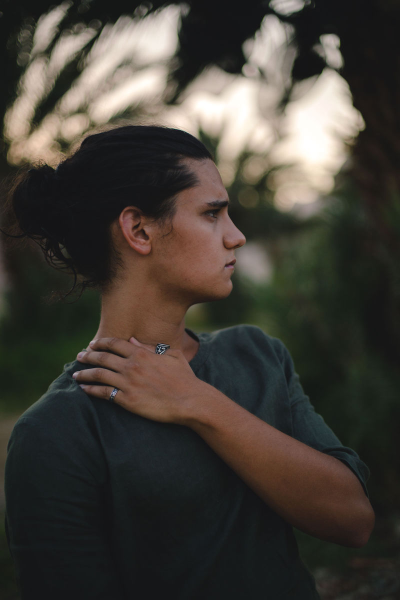 穿着灰色圆领衬衫的男子触摸左肩