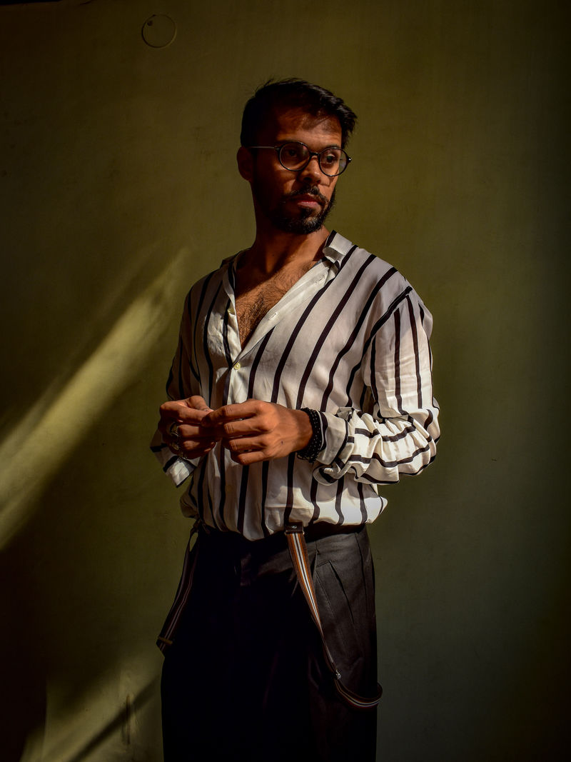 穿黑白条纹衬衫的男人站在灰色的W前面