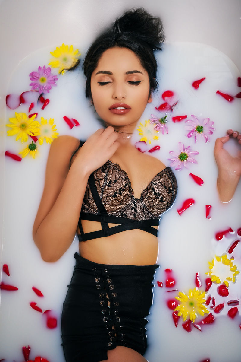 穿黑胸罩的女人躺在牛奶浴上