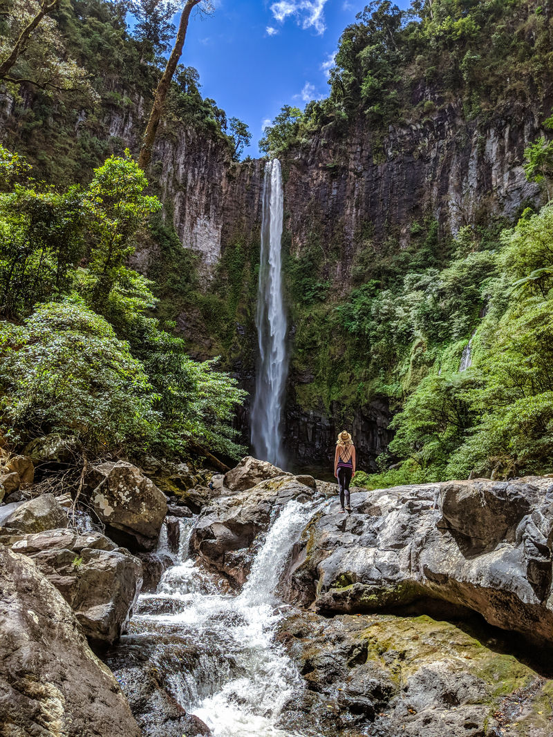 站在岩石上看瀑布的女人