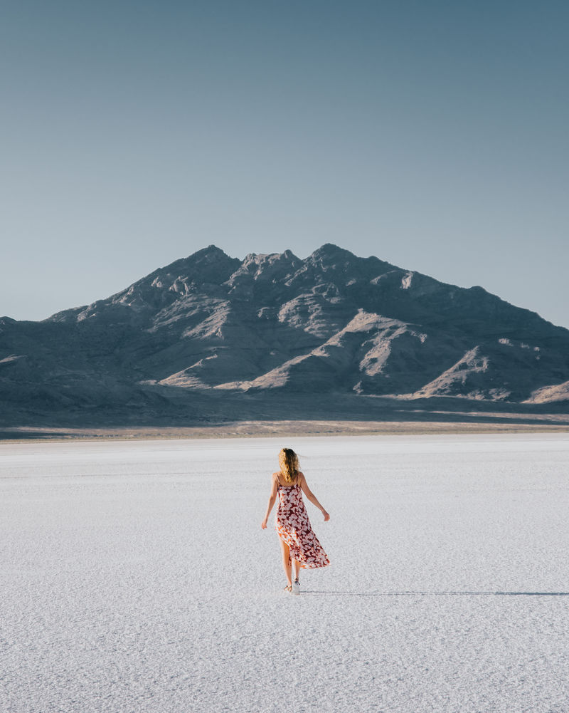 穿着衣服的女人在能看到山景的田野上行走