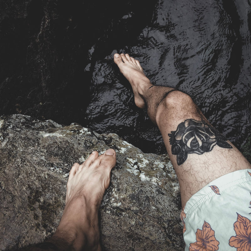 穿着白色花短裤的人坐在岩石上