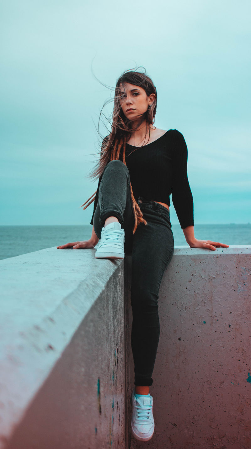 穿黑色长袖衬衫的女人坐在白色混凝土上